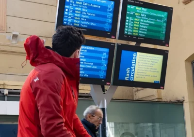 Un homme regarde le panneau des horaires de train à la gare - © Florian Garibal