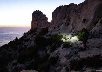 Une personne marche au crépuscule le long de l'arête des Goudes dans les calanques avec sa frontale - © Florian Garibal