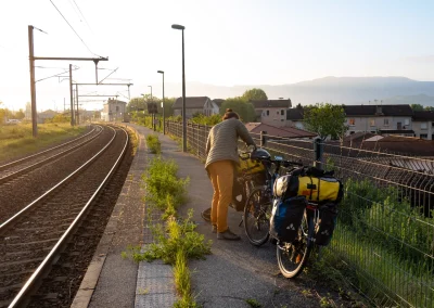 Un grimpeur au bord d'un quai avec des sacoches sur un vélo pour partir grimper avec de belles lumières du matin © Florian Garibal