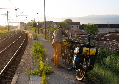 Un grimpeur au bord d'un quai avec des sacoches sur un vélo pour partir grimper avec de belles lumières du matin © Florian Garibal